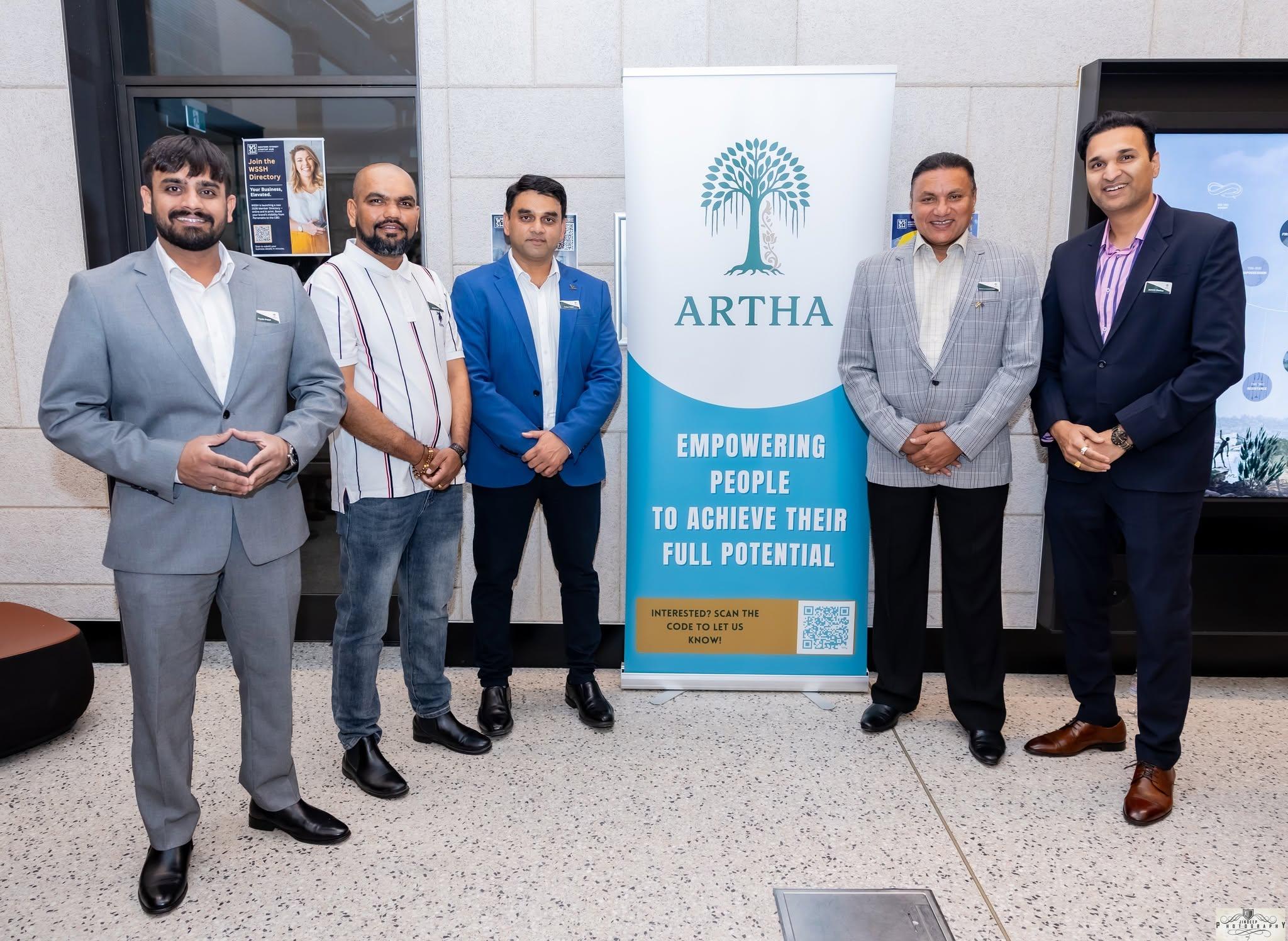 Five members in business attire either side of the Artha banner at a networking event