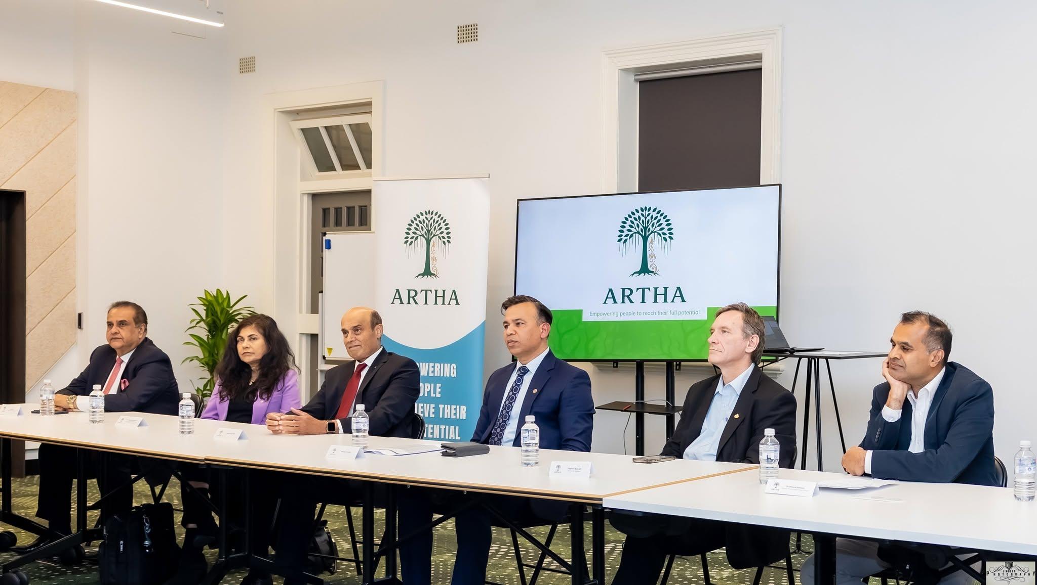 Panellists seated at the table beside the Artha banner during a panel discussion.